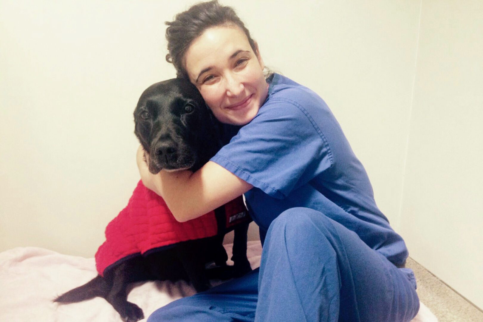 Veterinary surgeon cuddling black labrador in wards