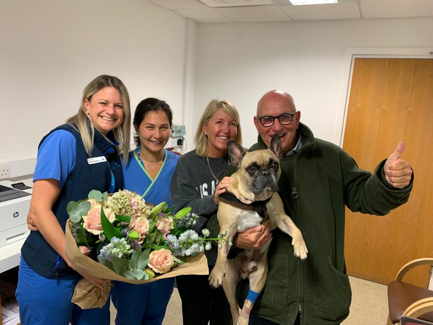 Family holding their French Bulldog with his veterinary team